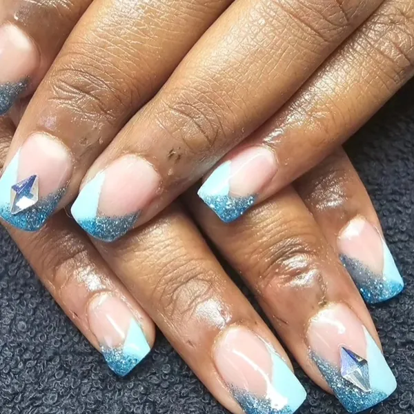 Vierkante nagels met lichtblauwe V-tips, blauwe glitter en steentjes